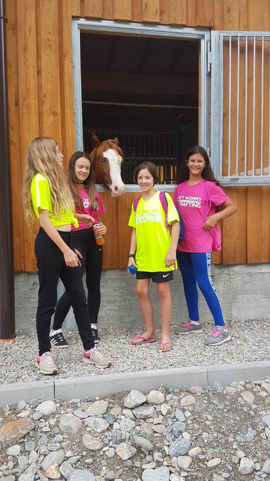 Ragazze del campus Sesia Rafting salutano i cavalli vicino alla stalla