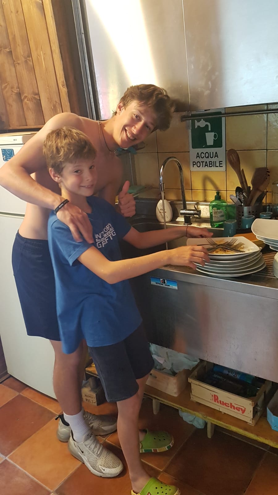 Ragazzi del campus Sesia Rafting  lavano i piatti in cucina.