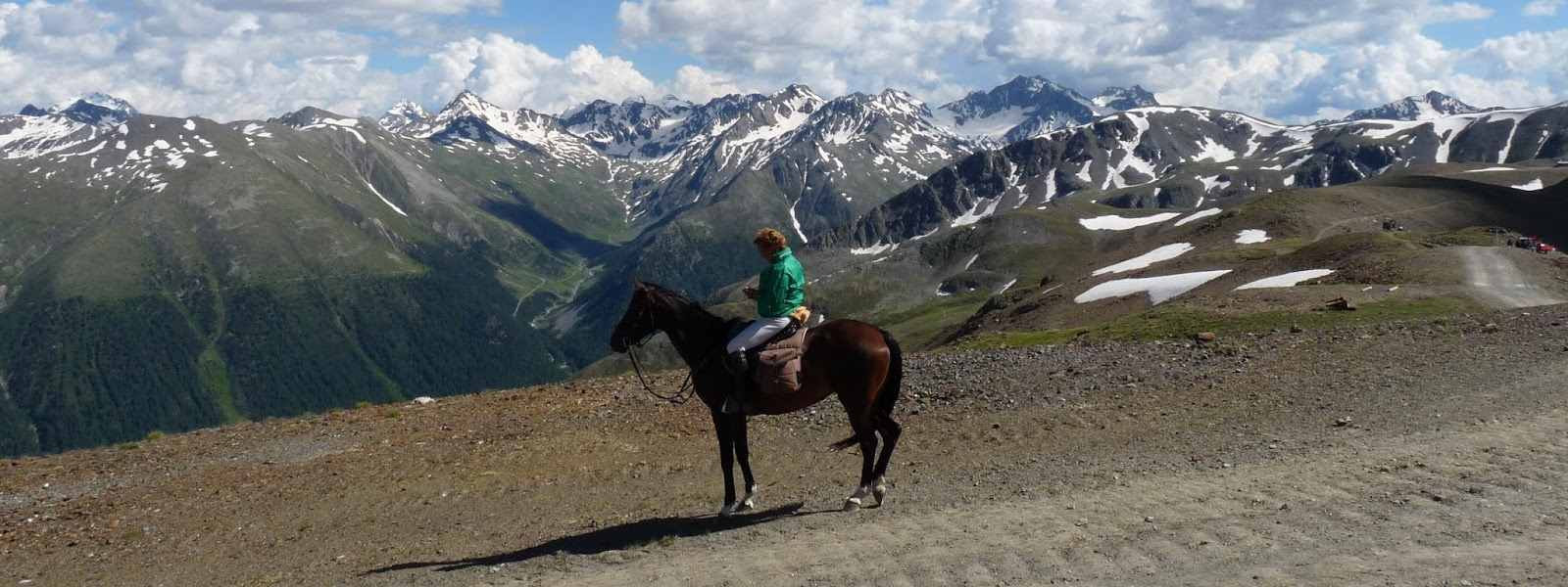 Trekking a cavallo con paesaggio di montagne innevate alle spalle